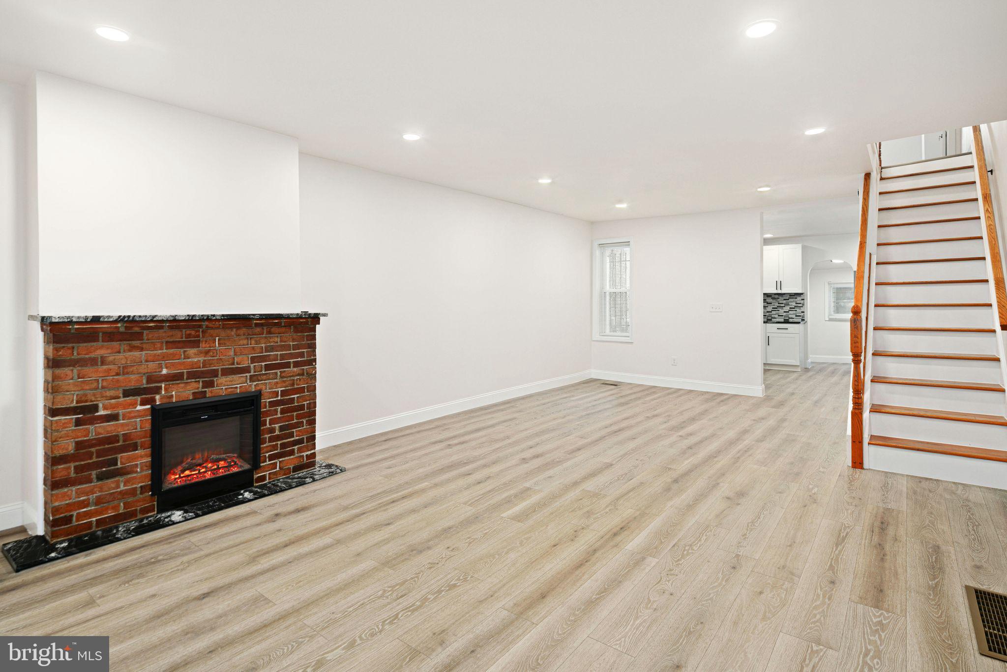 a view of an empty room with wooden floor fireplace and a window