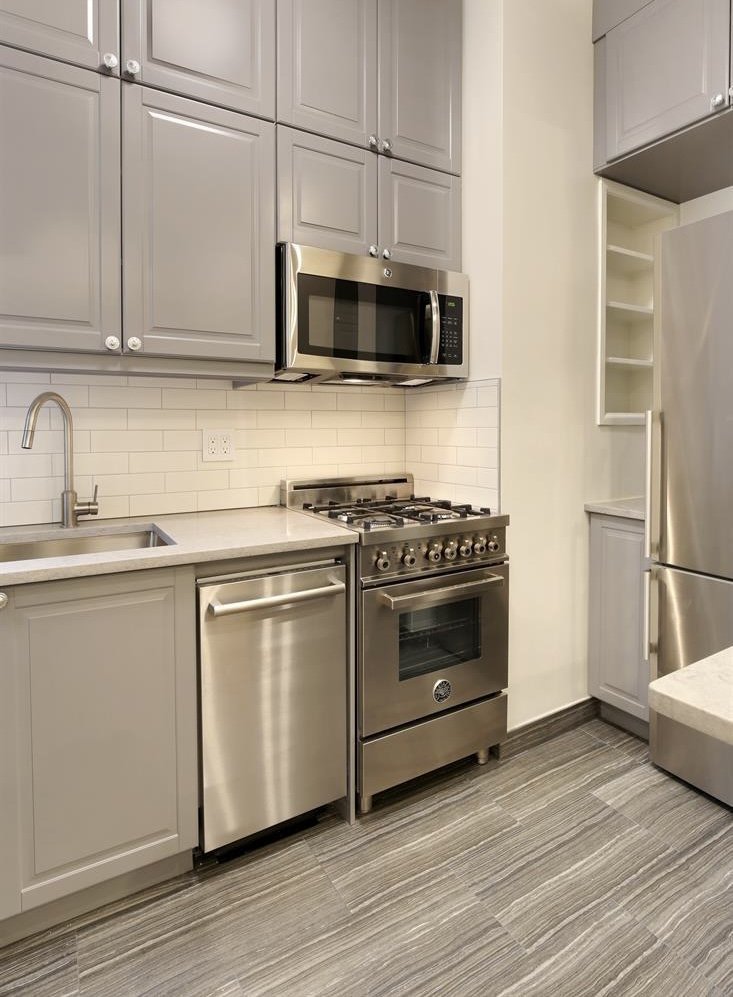 a kitchen with stainless steel appliances white cabinets and a stove top oven