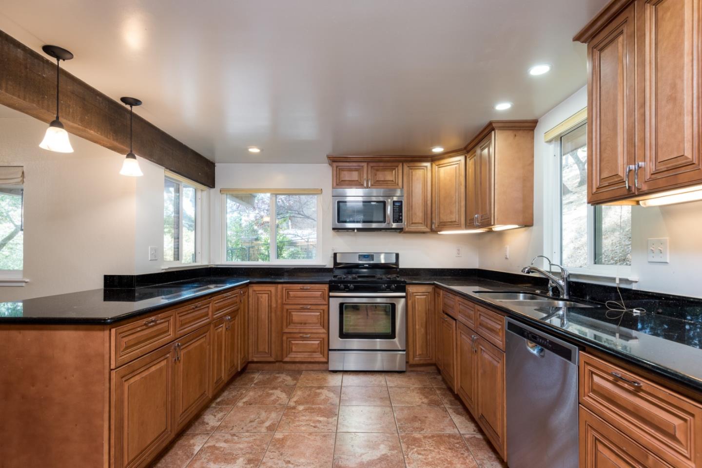 a kitchen with granite countertop a sink counter top space cabinets and stainless steel appliances