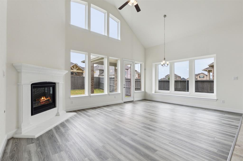 a view of an empty room with wooden floor fireplace and a window