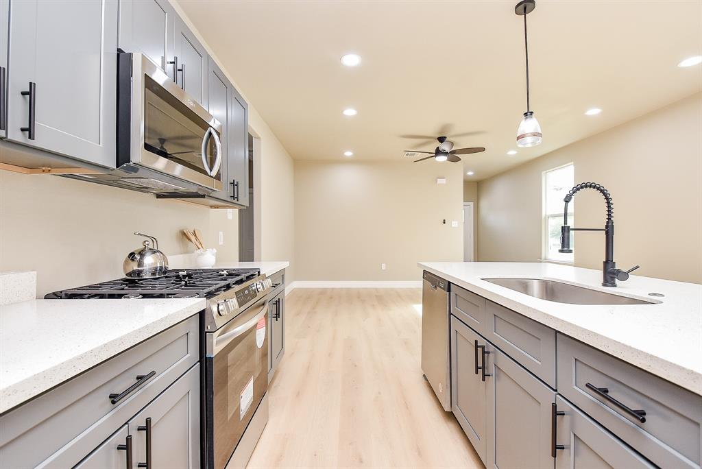 a kitchen with stainless steel appliances granite countertop a sink a stove and a wooden floors