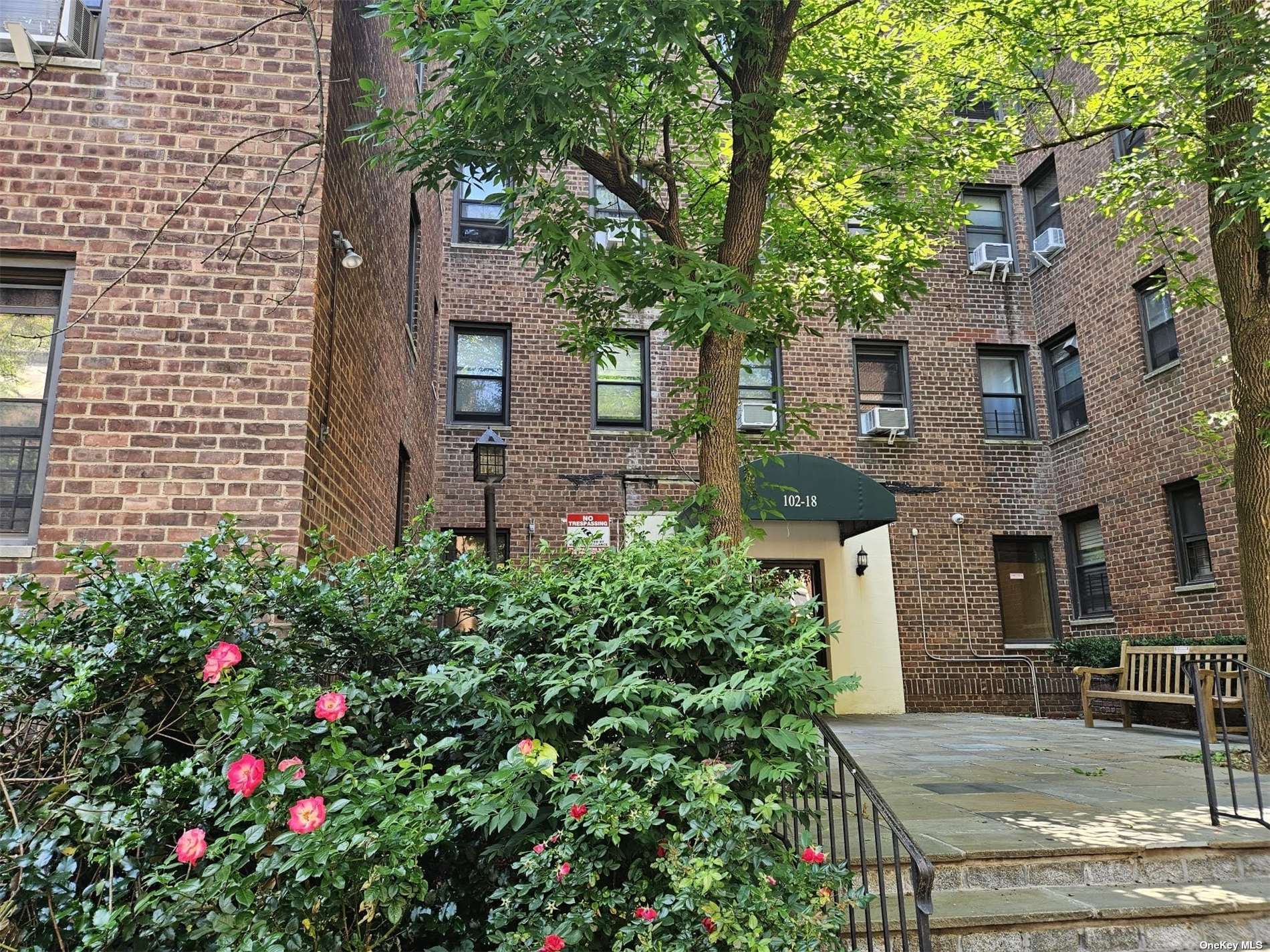 a view of a brick house with a flower garden