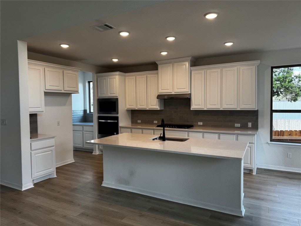 a kitchen with kitchen island a sink a stove a refrigerator and white cabinets