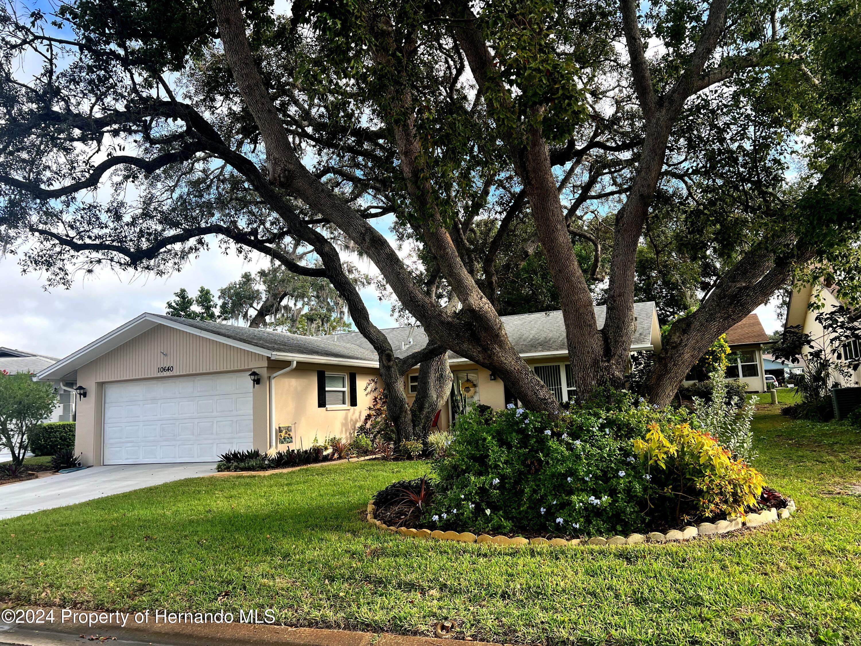 a front view of a house with a garden and trees