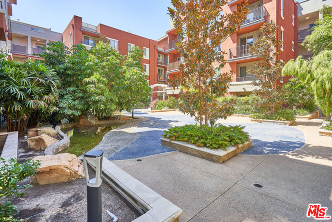 a front view of a multi story residential apartment building with yard and bench