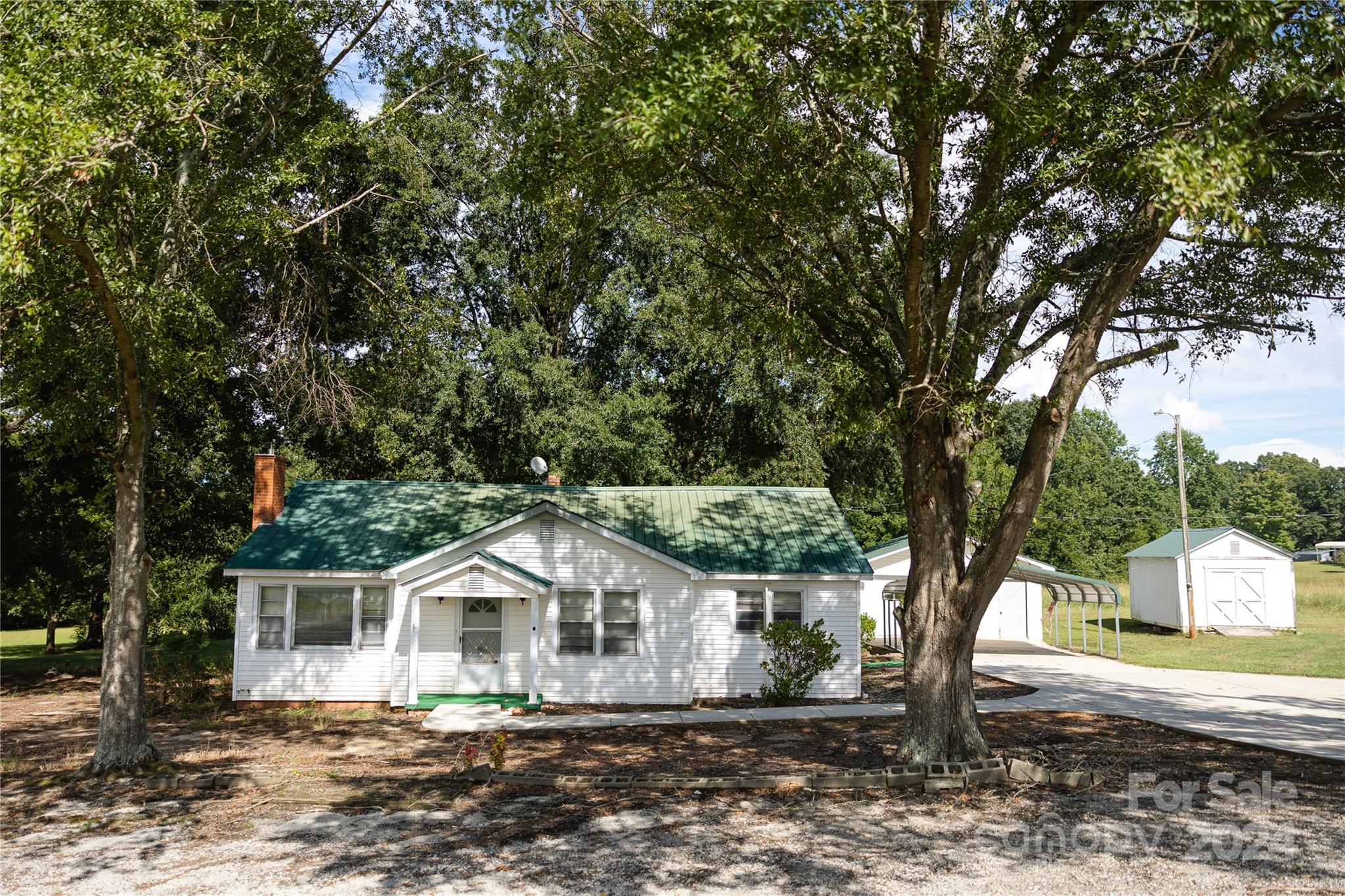 a front view of a house with a yard and large trees