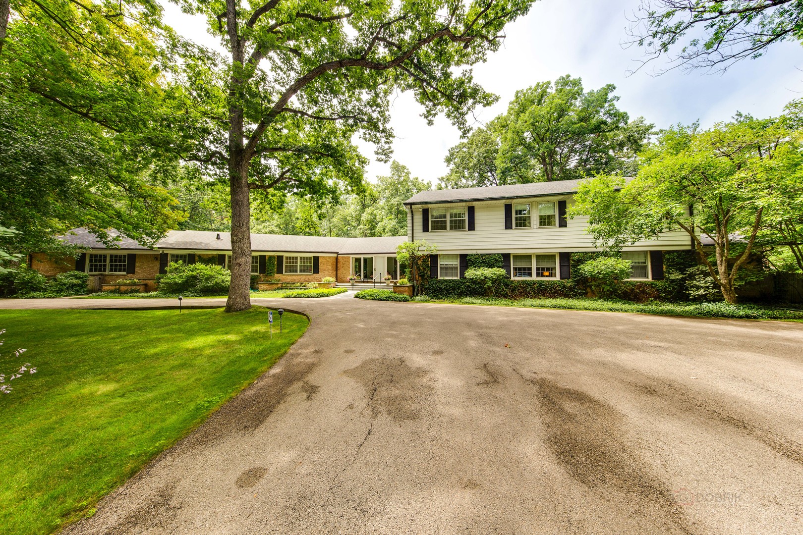 a view of a house with a big yard and large trees