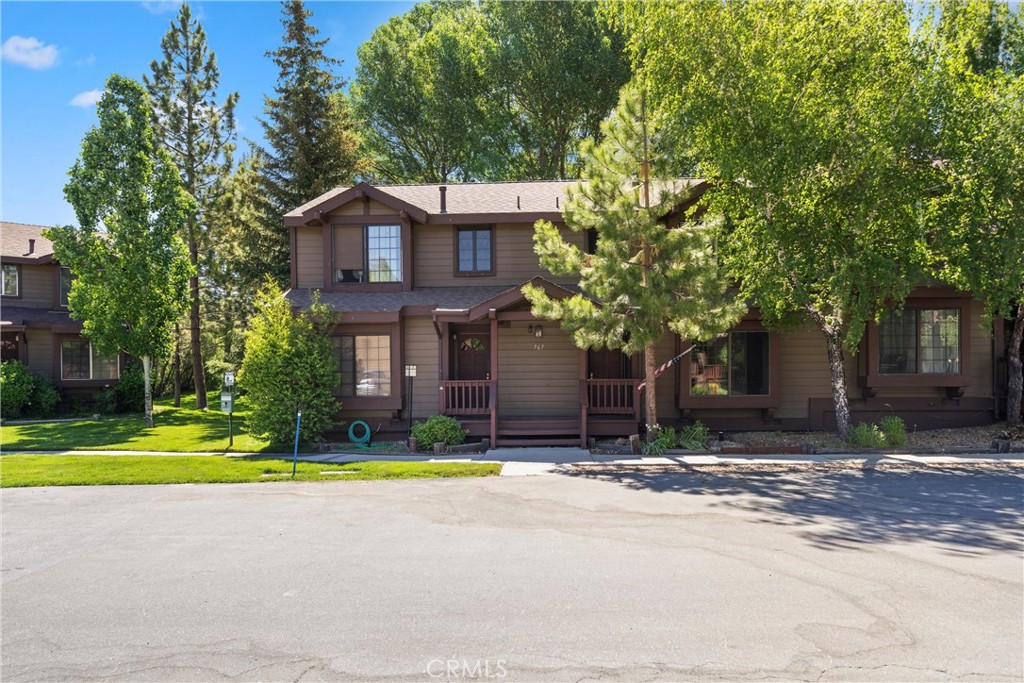 a house that has a big yard and a large trees with wooden fence