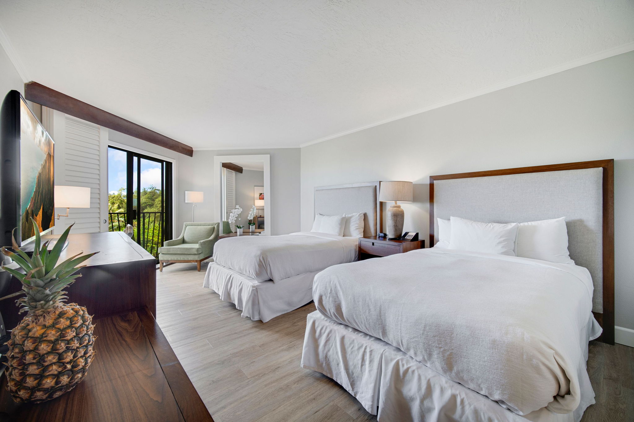 a spacious bedroom with two beds and a potted plant