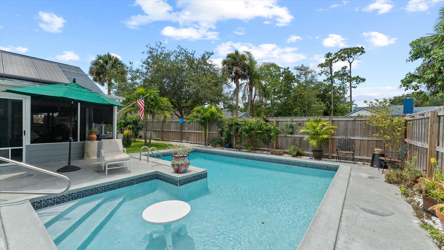 a view of a patio with couches table and chairs with potted plants and big yard