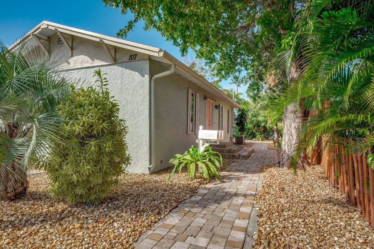 a backyard of a house with potted plants and large tree