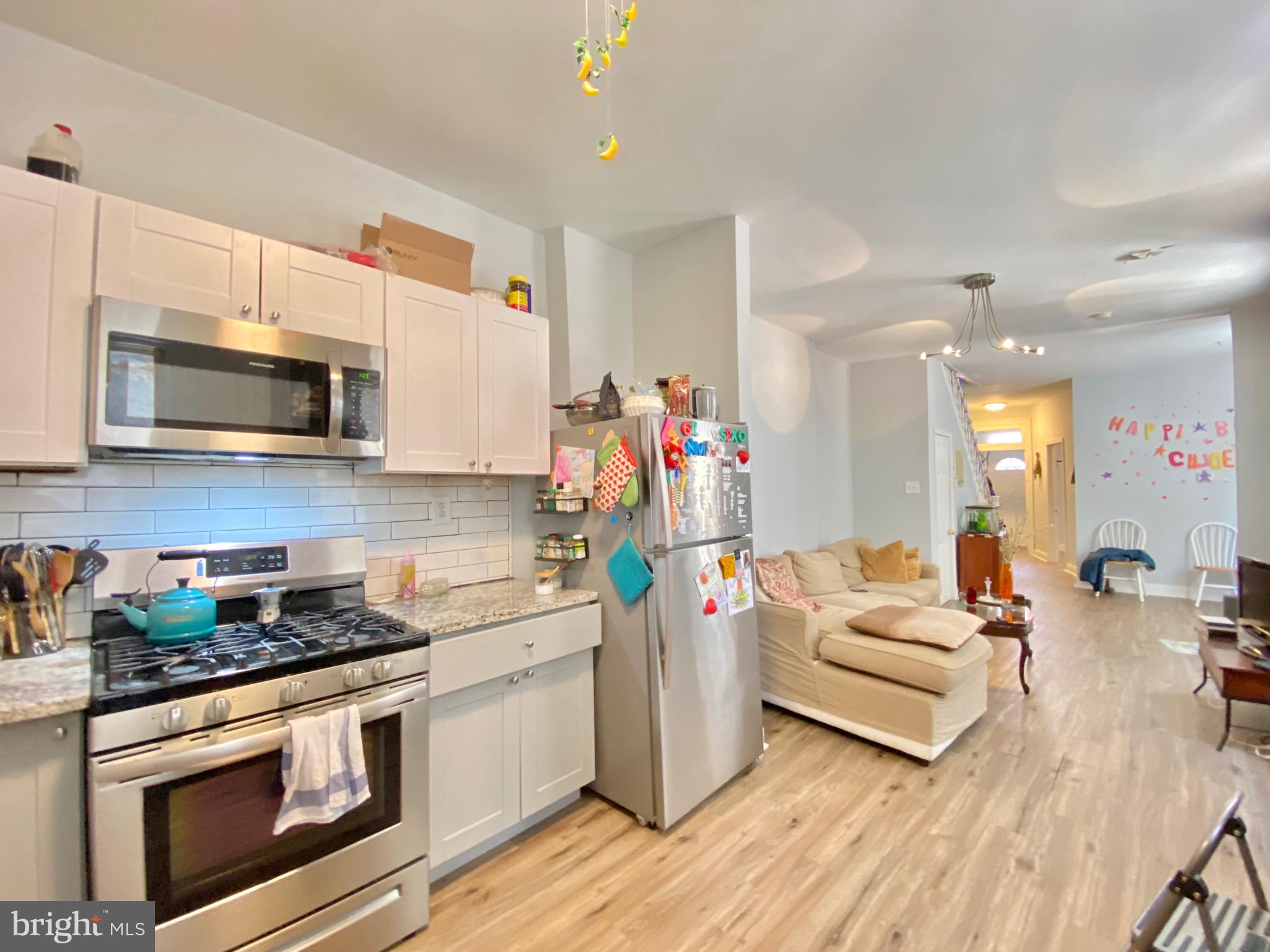 a kitchen that has a lot of white cabinets and stainless steel appliances