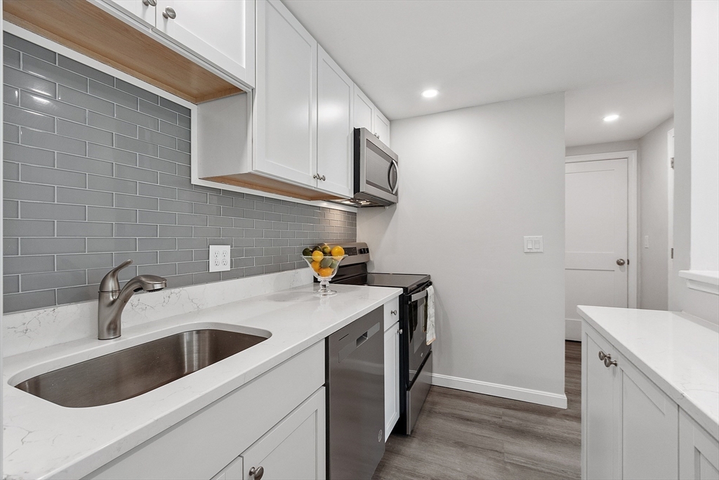 a kitchen that has a sink and a stove with wooden floor