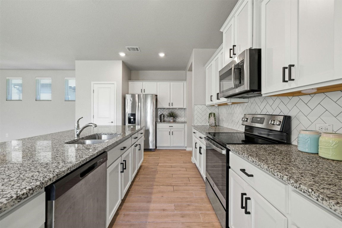 a large kitchen with stainless steel appliances granite countertop a lot of counter space and a sink