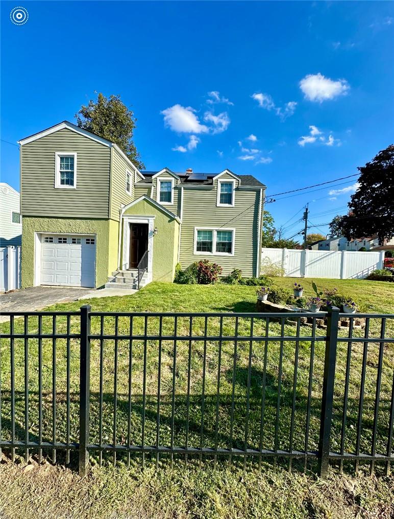 View of front facade featuring a front lawn and a garage