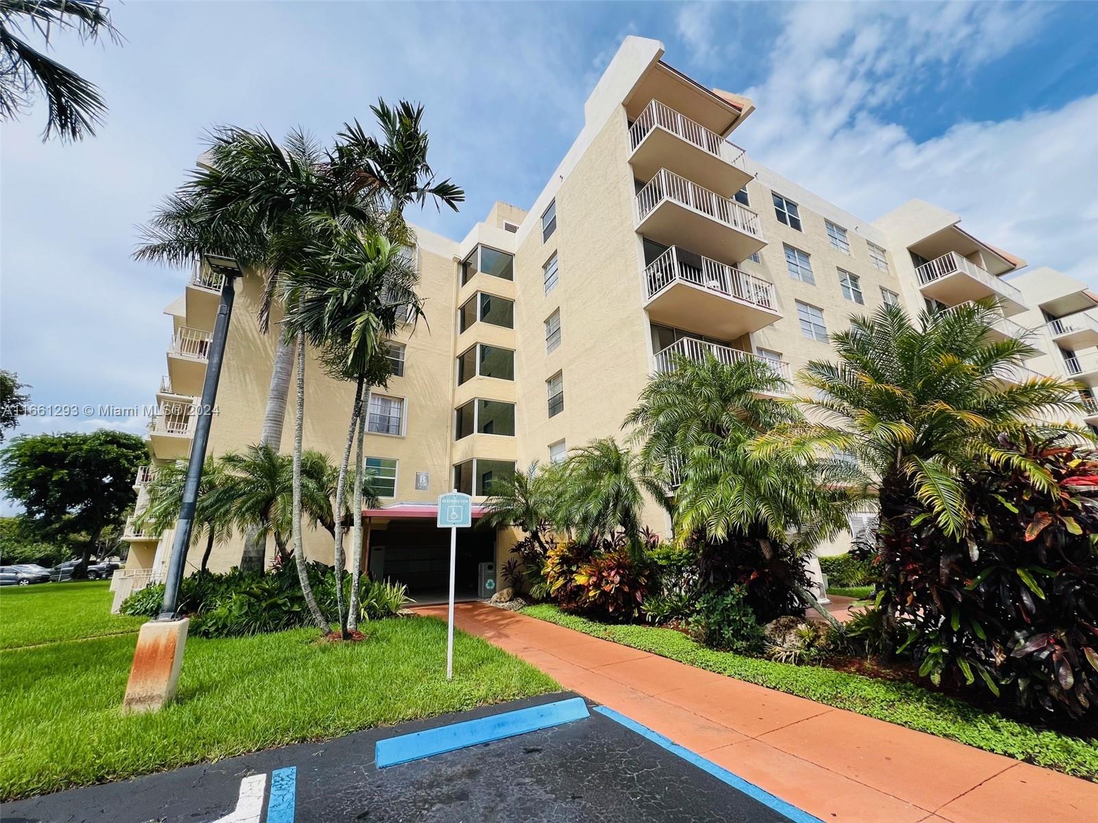 a front view of multi story residential apartment building with yard and green space