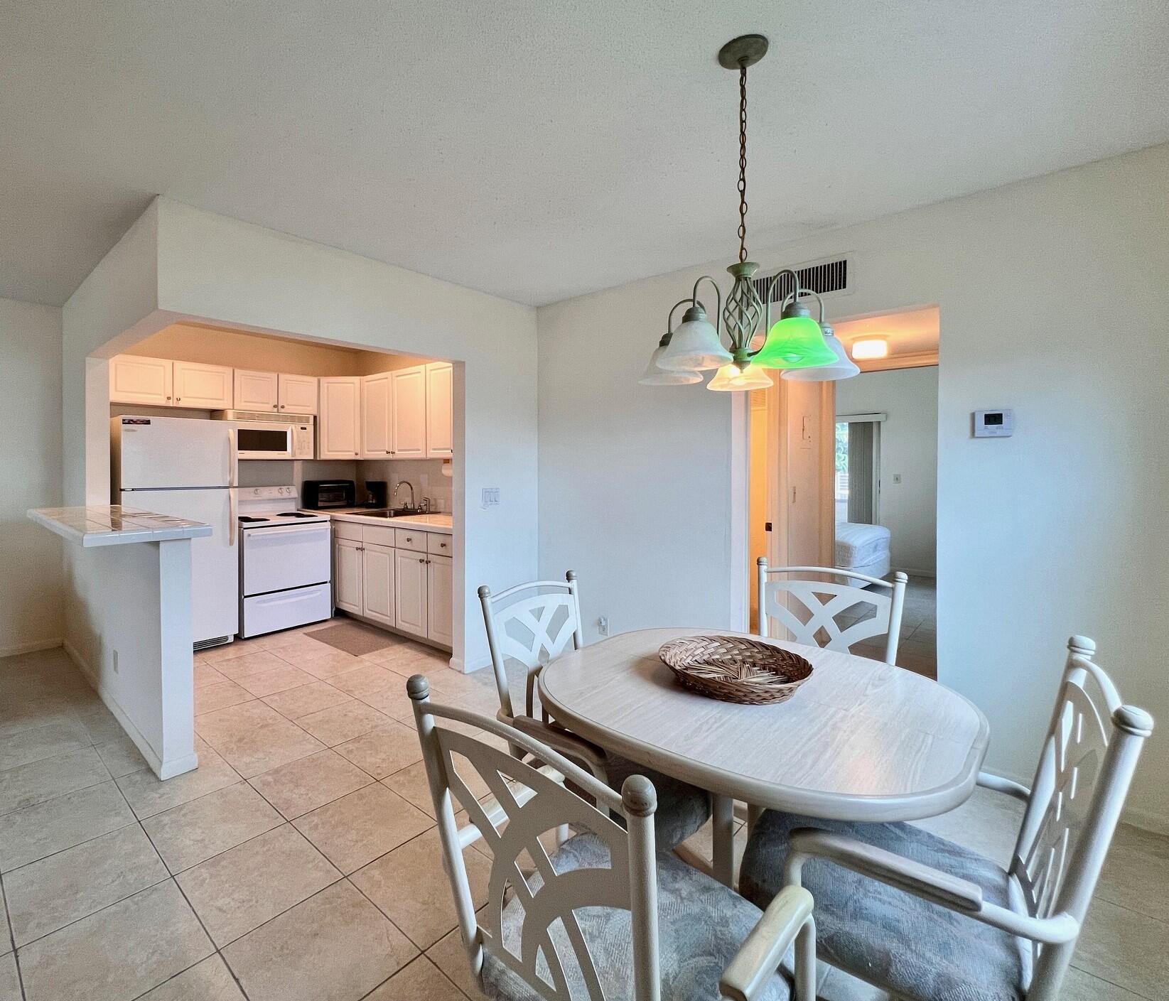 a kitchen with kitchen island a dining table chairs stainless steel appliances and cabinets