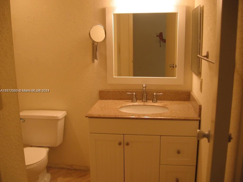 a bathroom with a granite countertop toilet sink and mirror