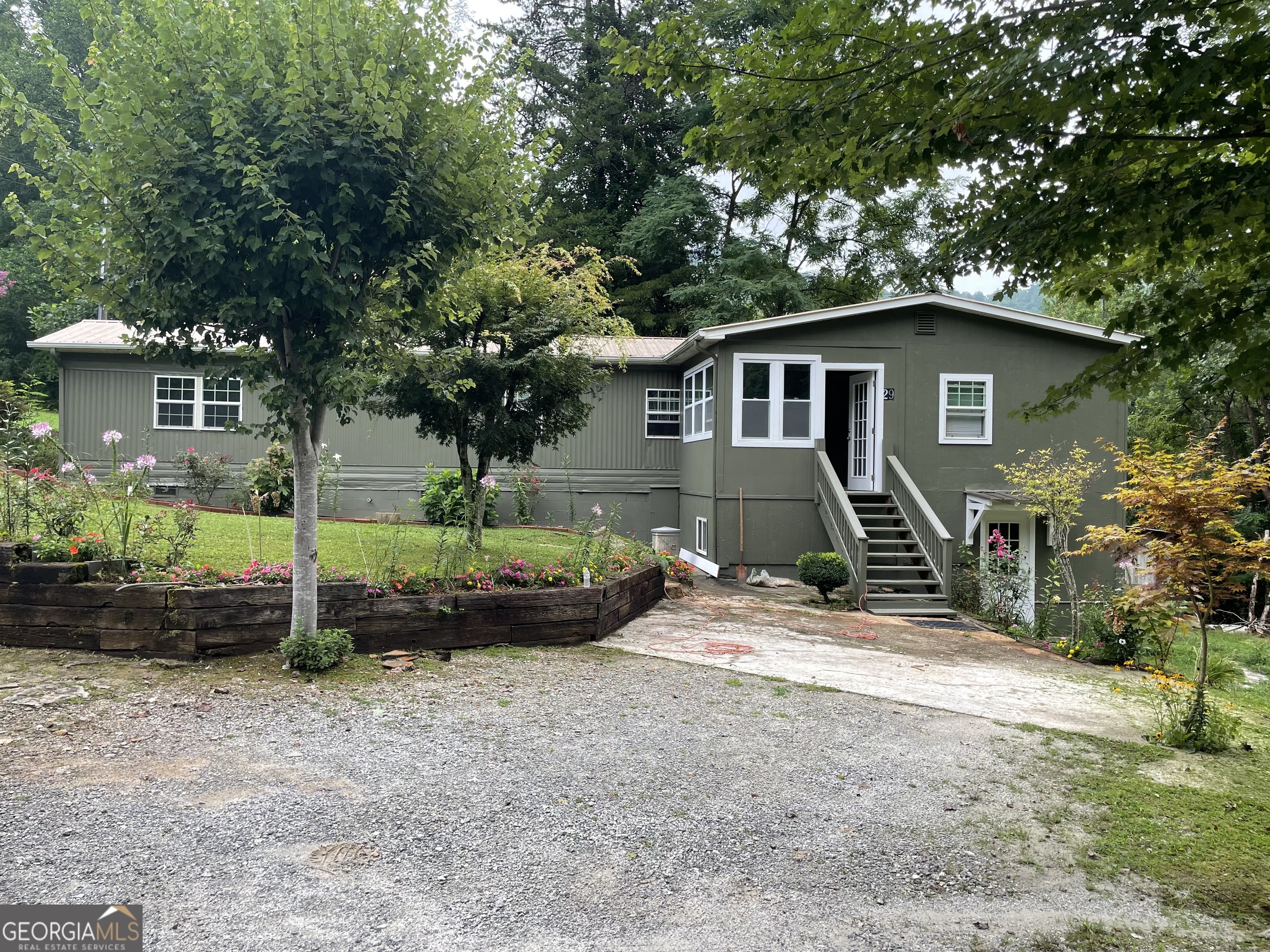 a view of a barn house in front of a yard with potted plants