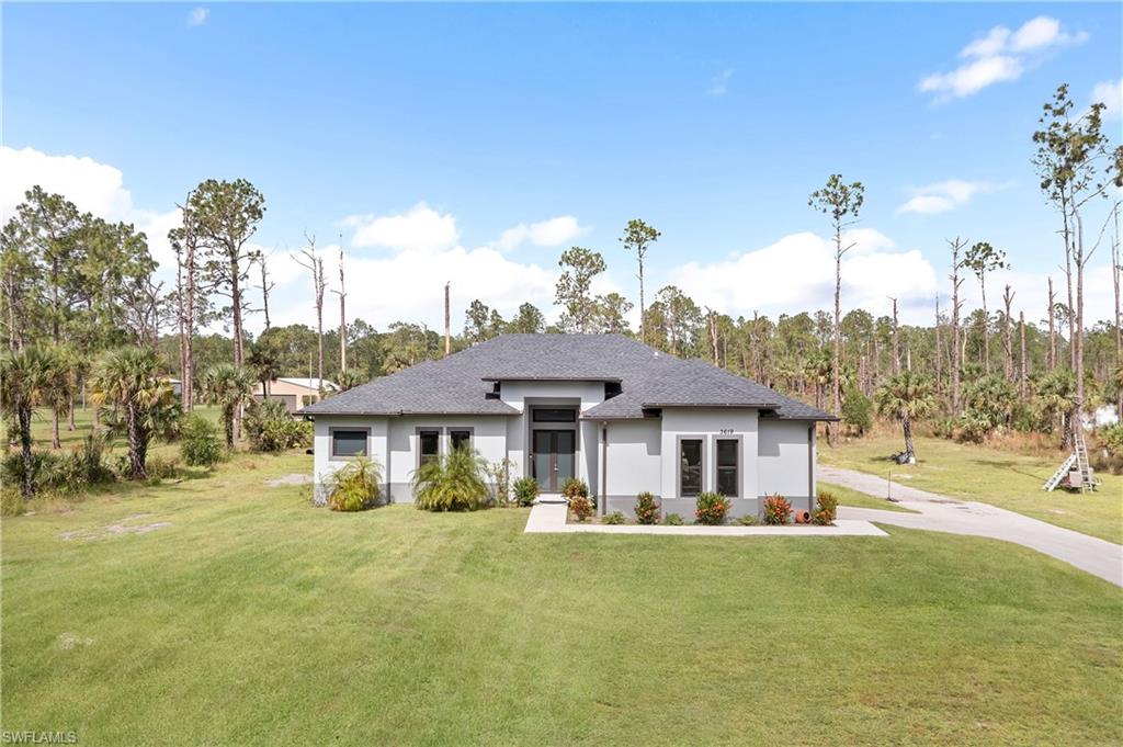 a view of a house with a big yard and palm trees