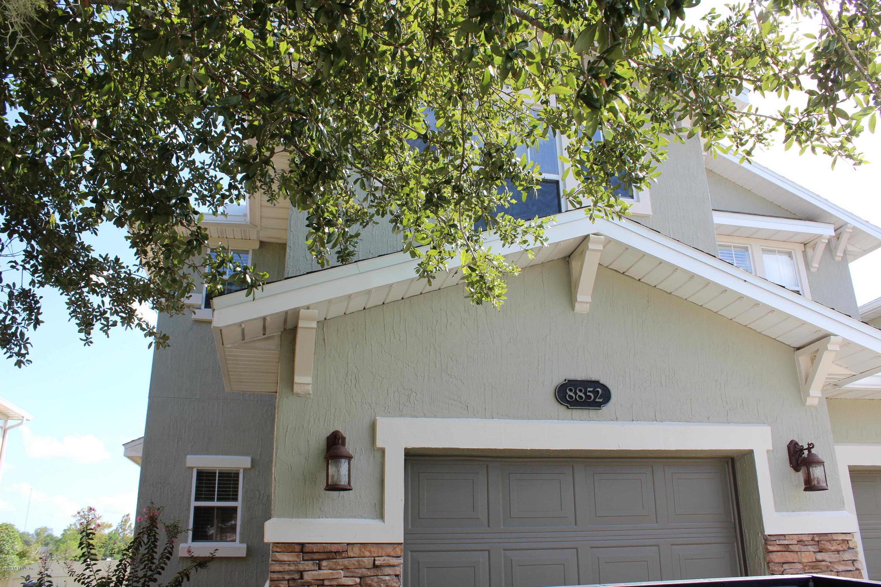 a front view of a house with a tree