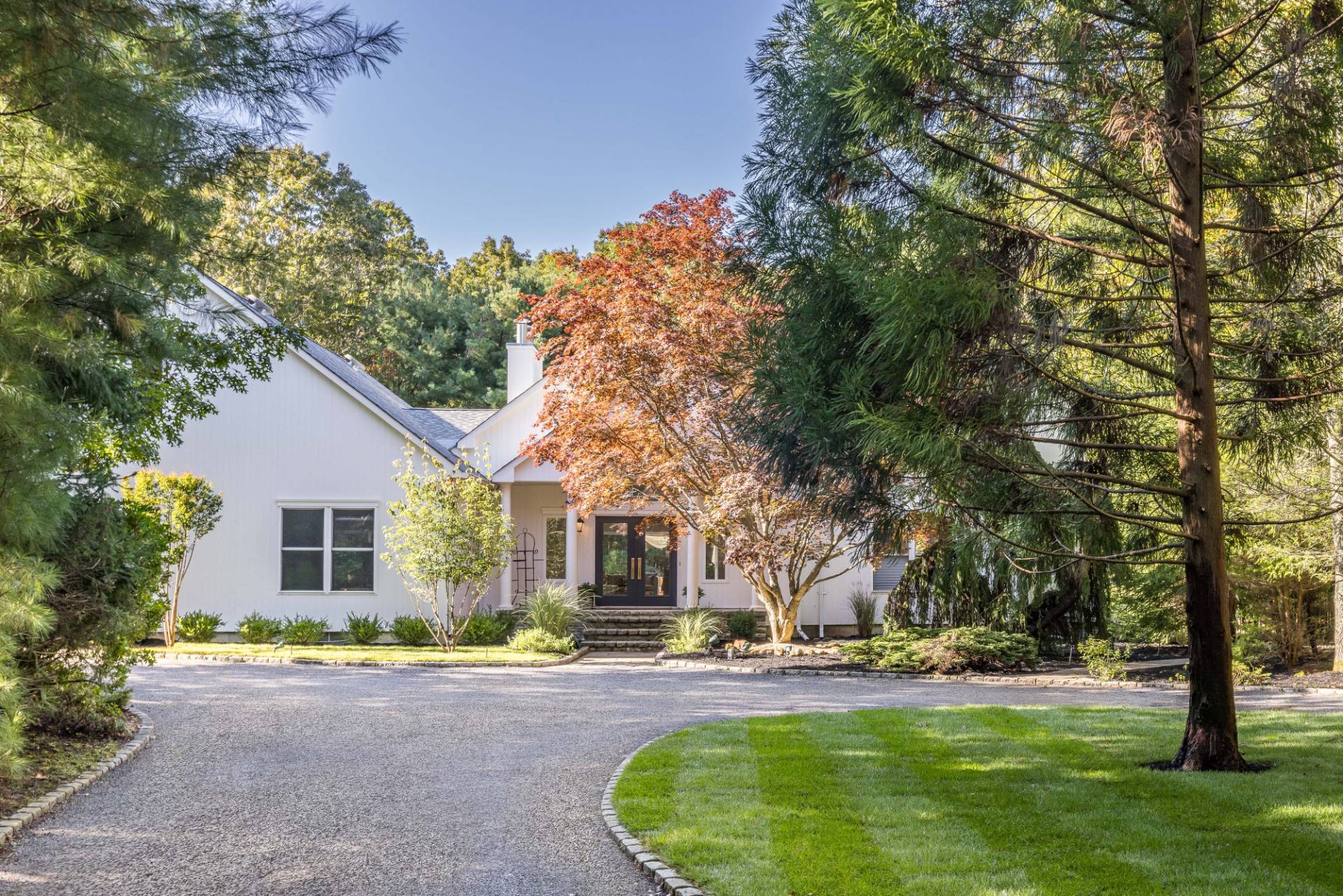 a front view of a house with a garden and trees