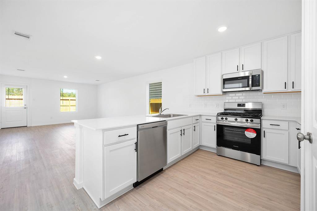 a kitchen with granite countertop a stove a sink and a microwave