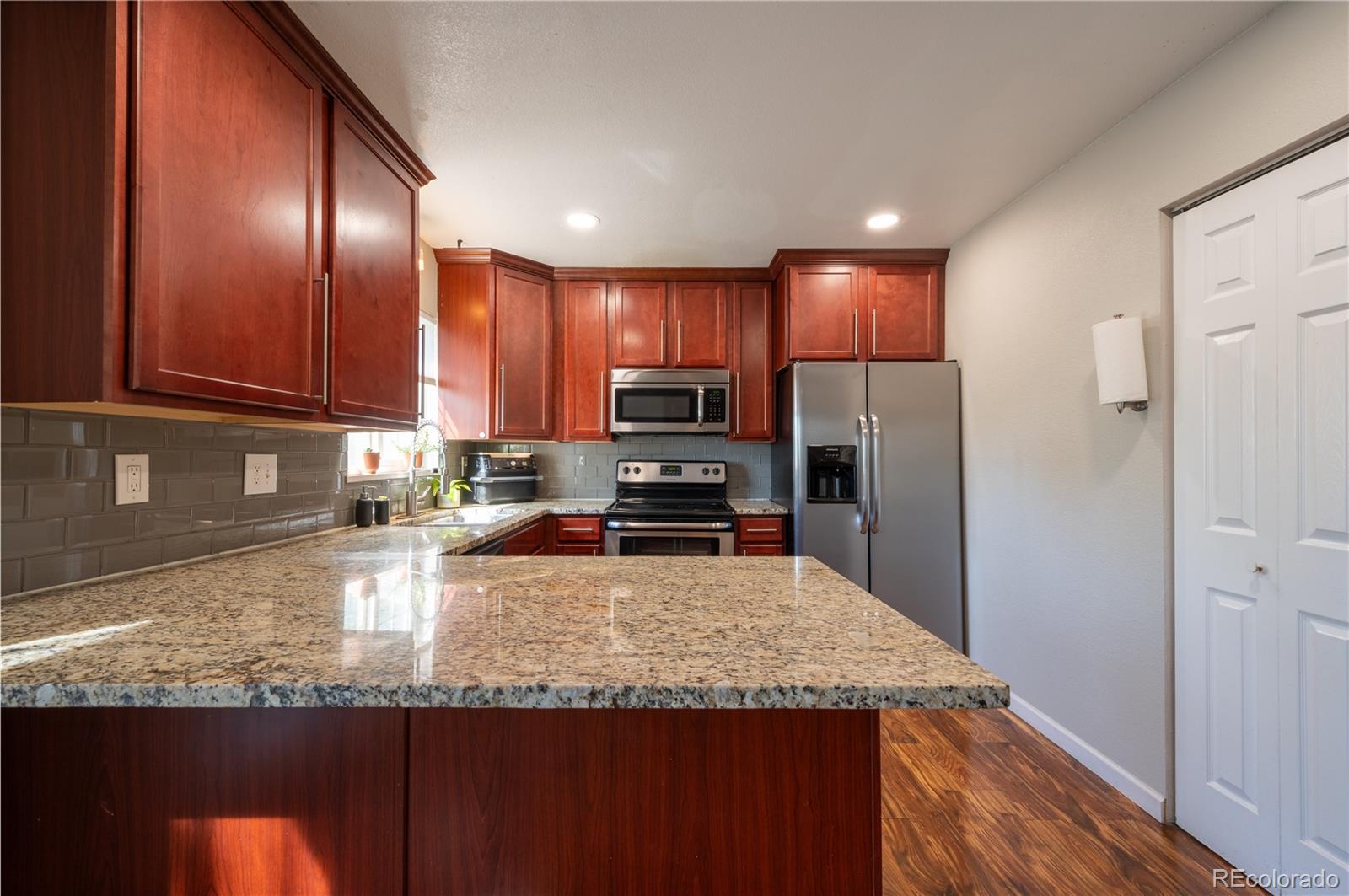 a kitchen with granite countertop stainless steel appliances a refrigerator and a sink