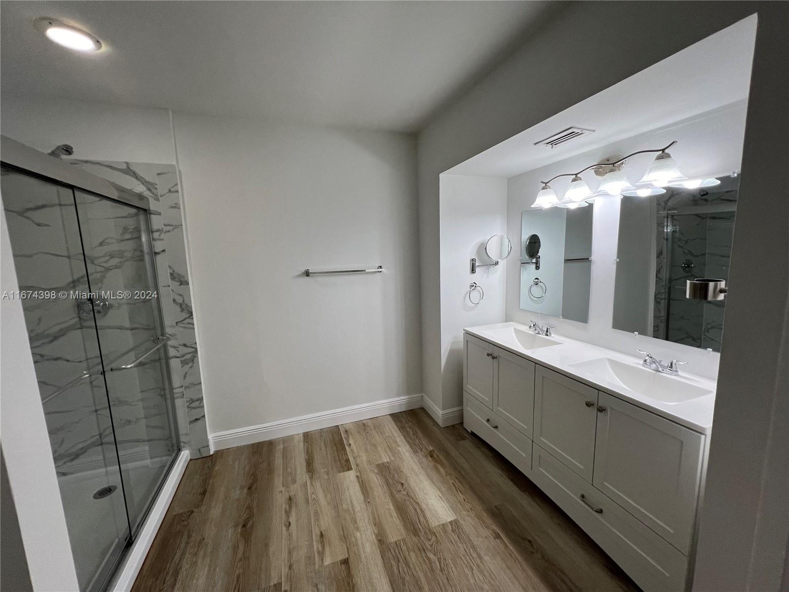 a bathroom with a sink mirror and shower