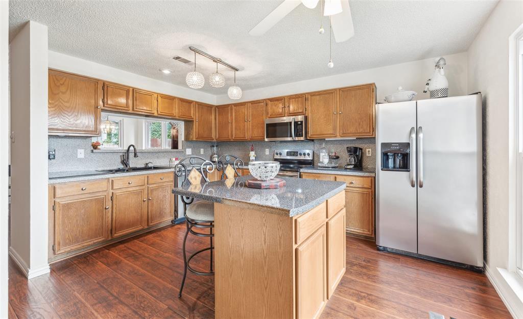 a kitchen with kitchen island granite countertop wooden cabinets and white appliances