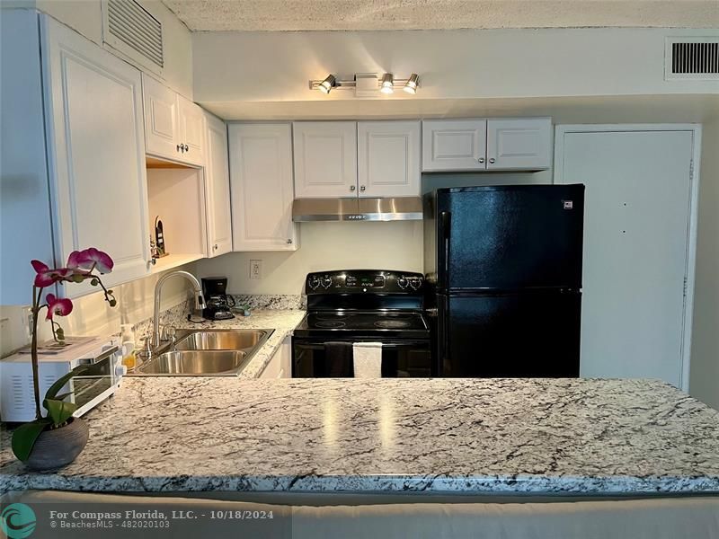 a kitchen with granite countertop a refrigerator stove and sink