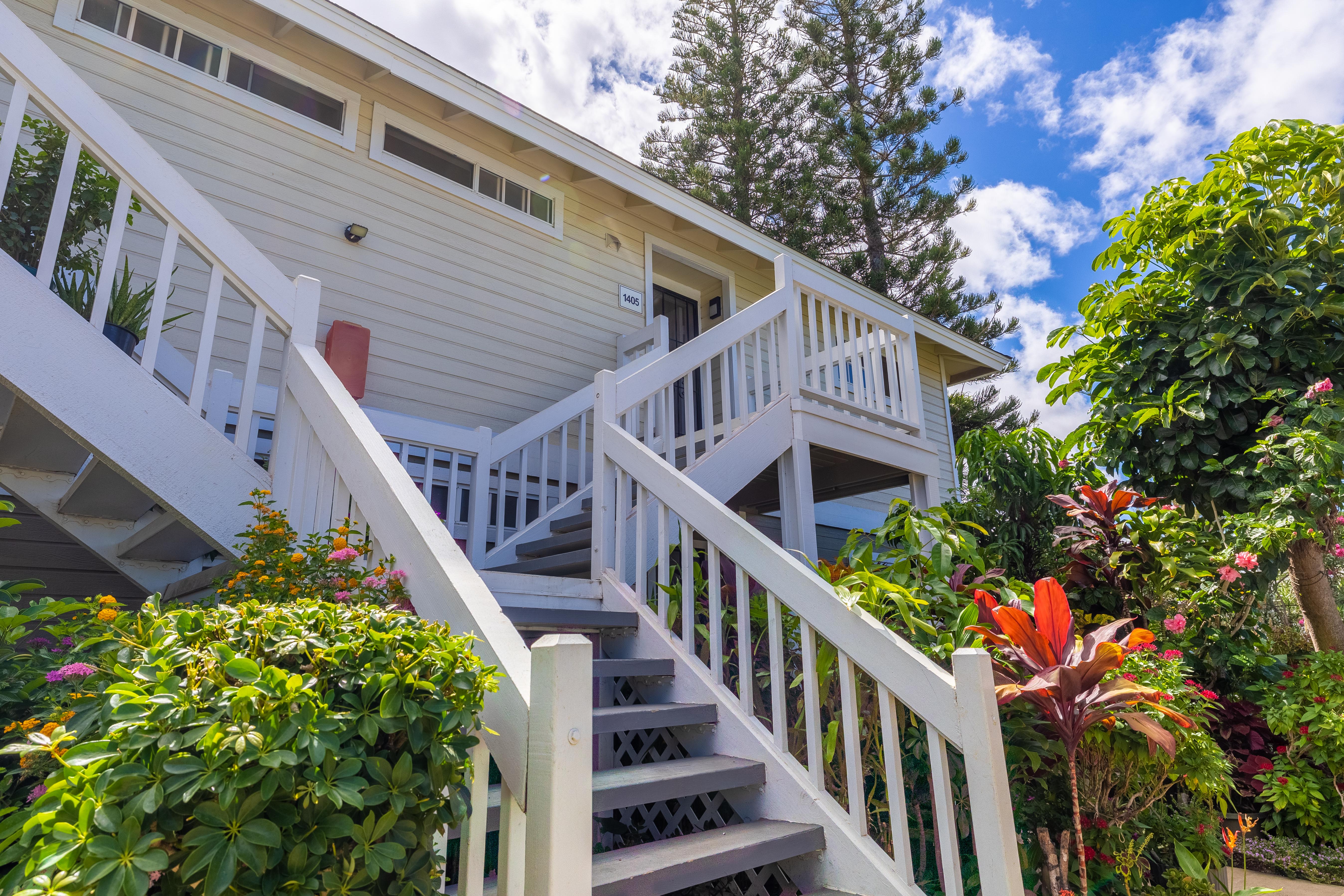 a view of an house with wooden stairs and a flower garden