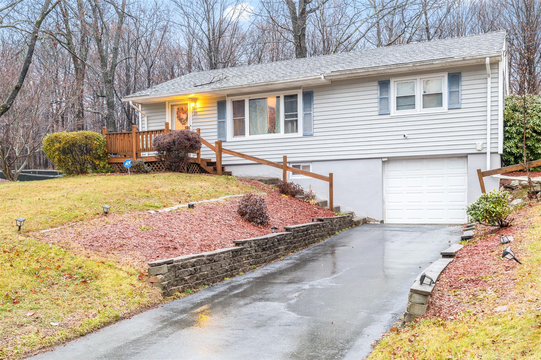 Single story home featuring a garage, a deck, and a front yard