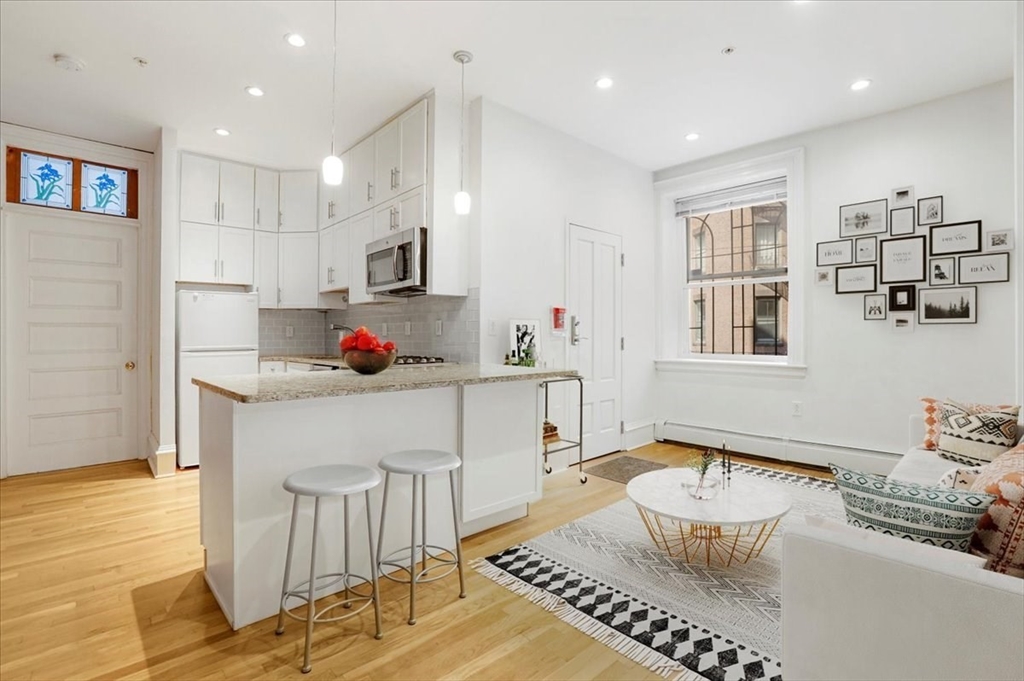 a living room with kitchen island furniture a flat screen tv and a table