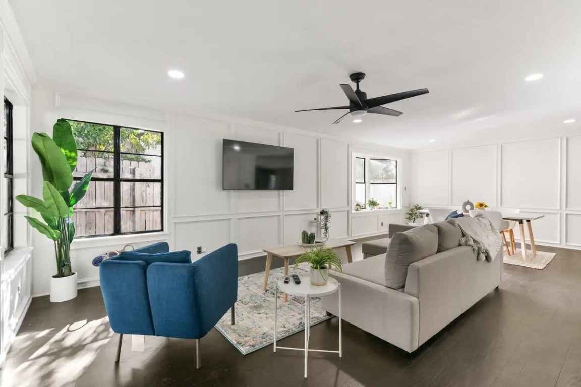 a living room with furniture a ceiling fan and a flat screen tv