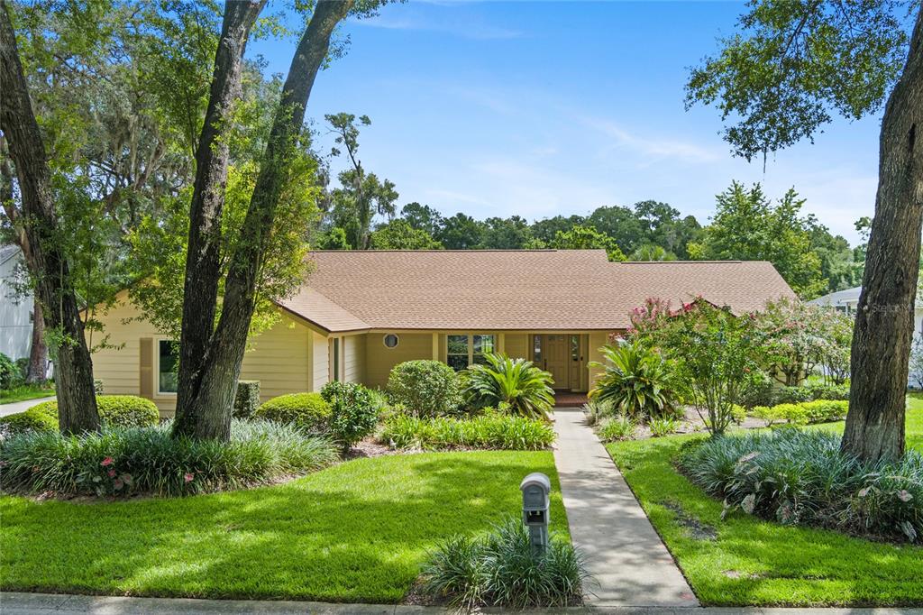 a aerial view of a house in a big yard with potted plants and large trees