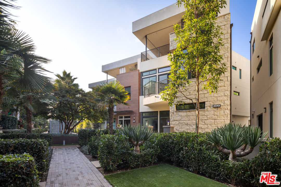 a front view of a multi story residential apartment building with yard and retail shops