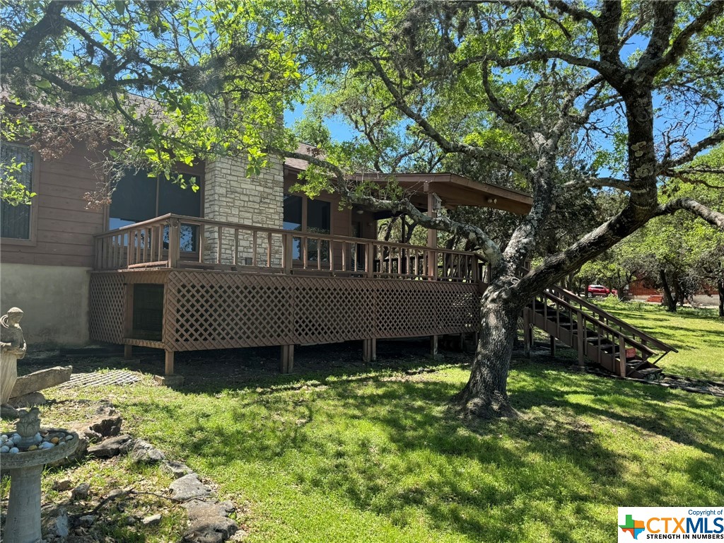 a view of a house with a yard and a wooden deck