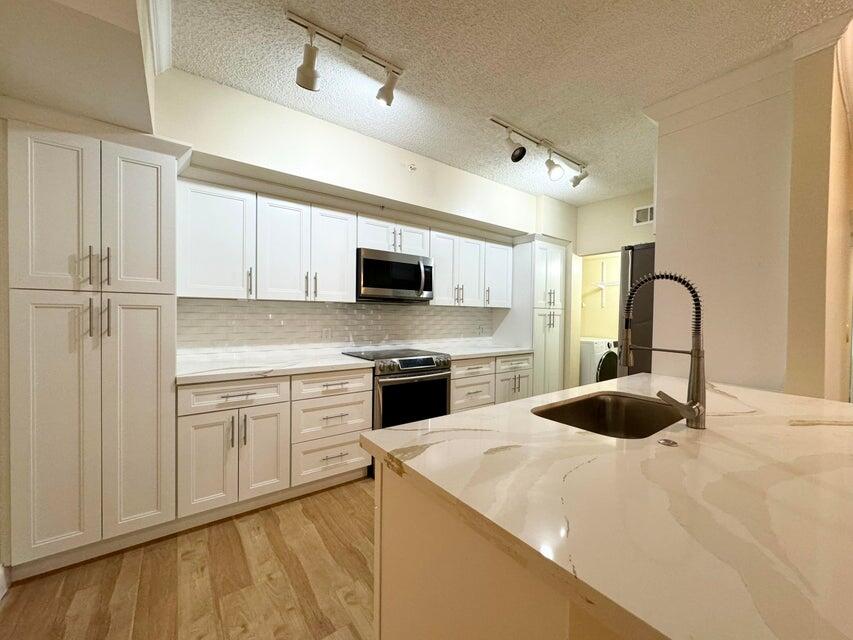 a kitchen with a sink white cabinets and stainless steel appliances