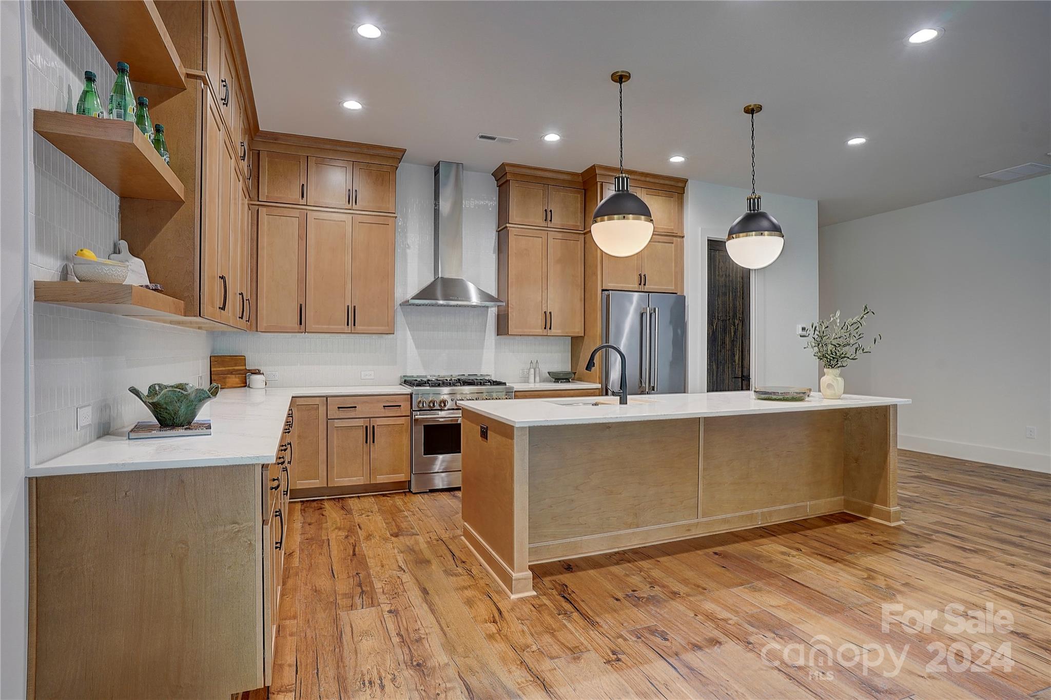 a large kitchen with stainless steel appliances a large counter top a stove and a sink