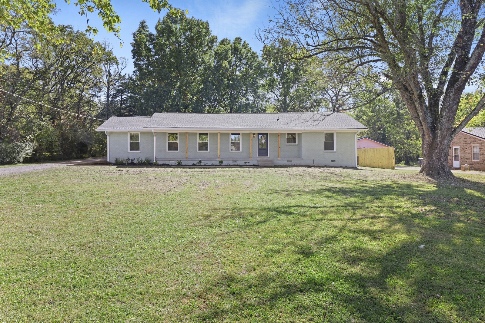 a view of a house with a yard and large trees