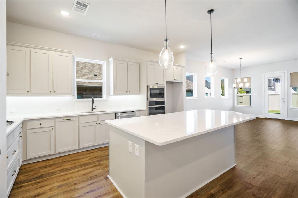 a large kitchen with stainless steel appliances kitchen island granite countertop a sink a stove and a wooden floors