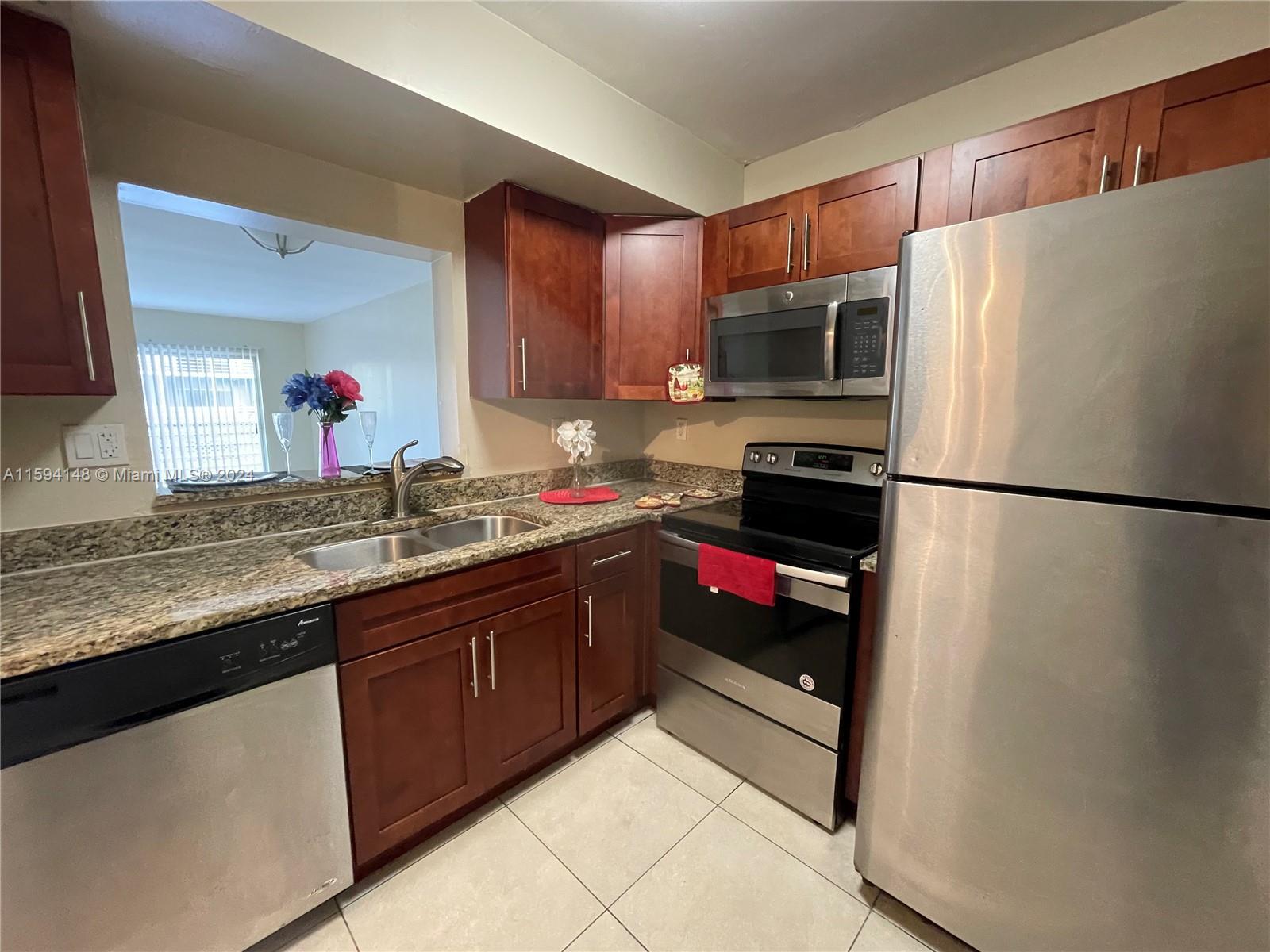 a kitchen with granite countertop a refrigerator and a sink