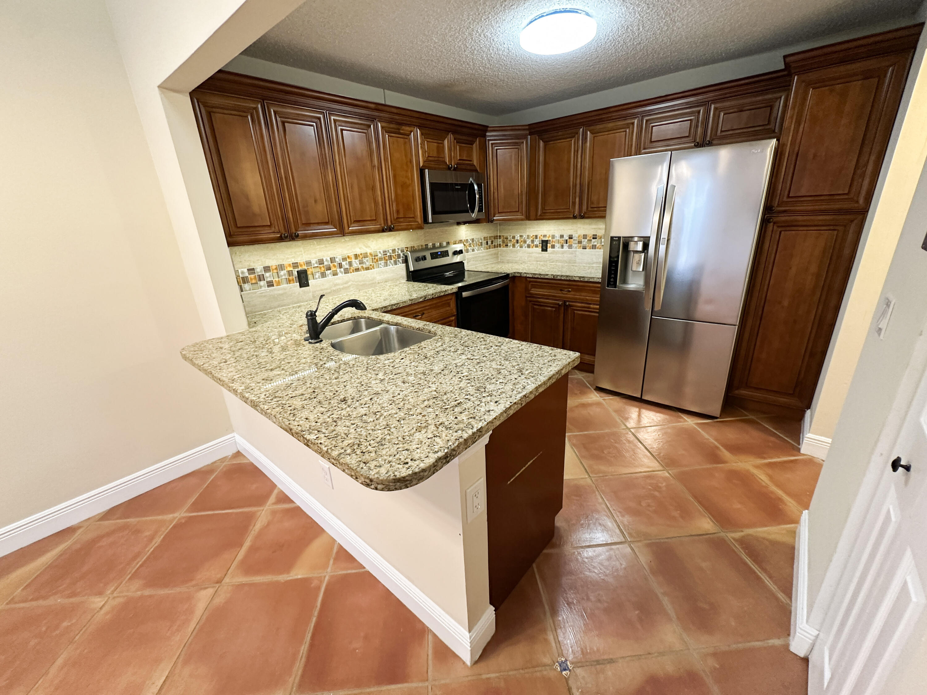 a kitchen with stainless steel appliances granite countertop a refrigerator sink stove microwave and cabinets