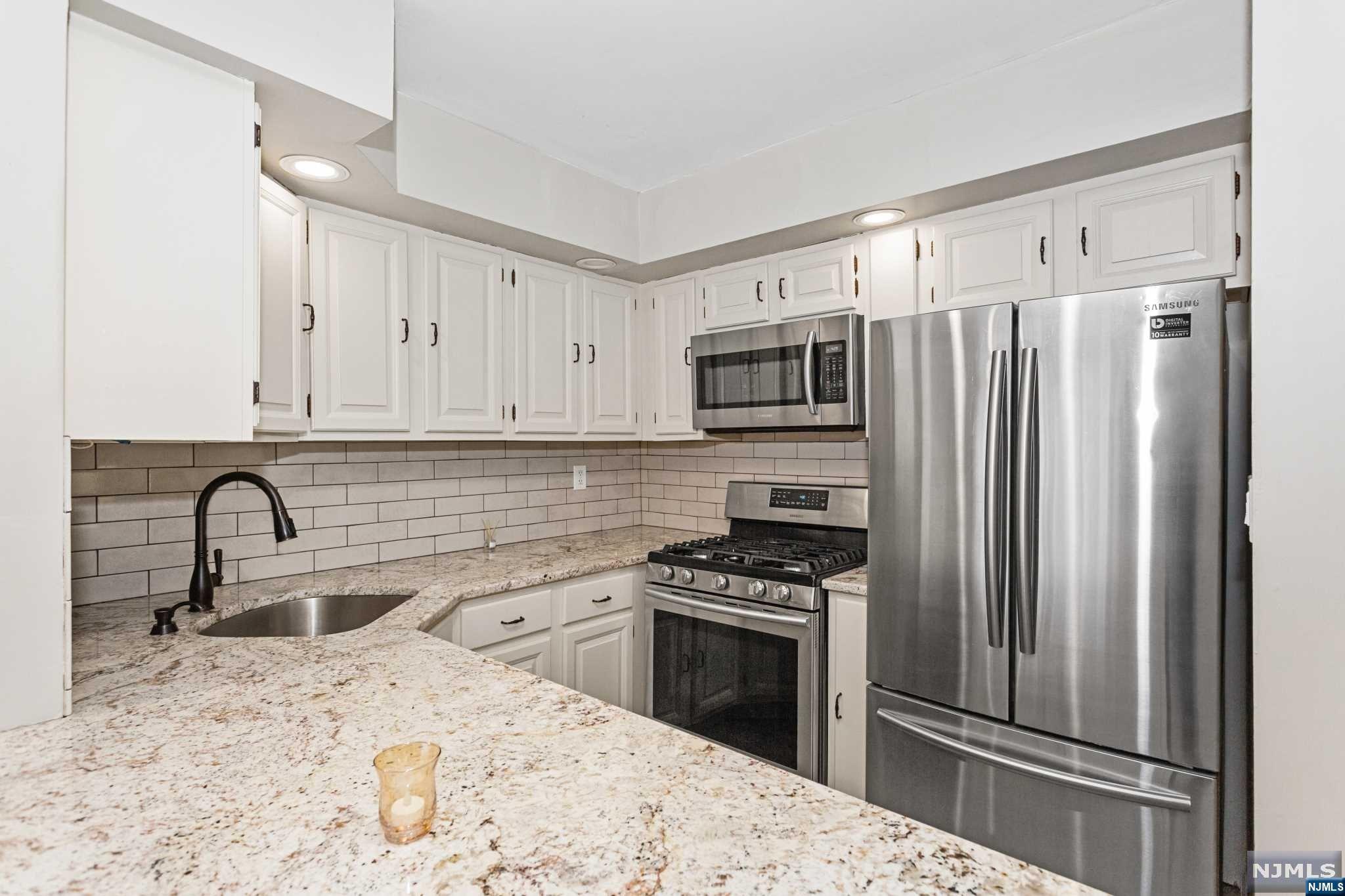 a kitchen with granite countertop a refrigerator stove and sink