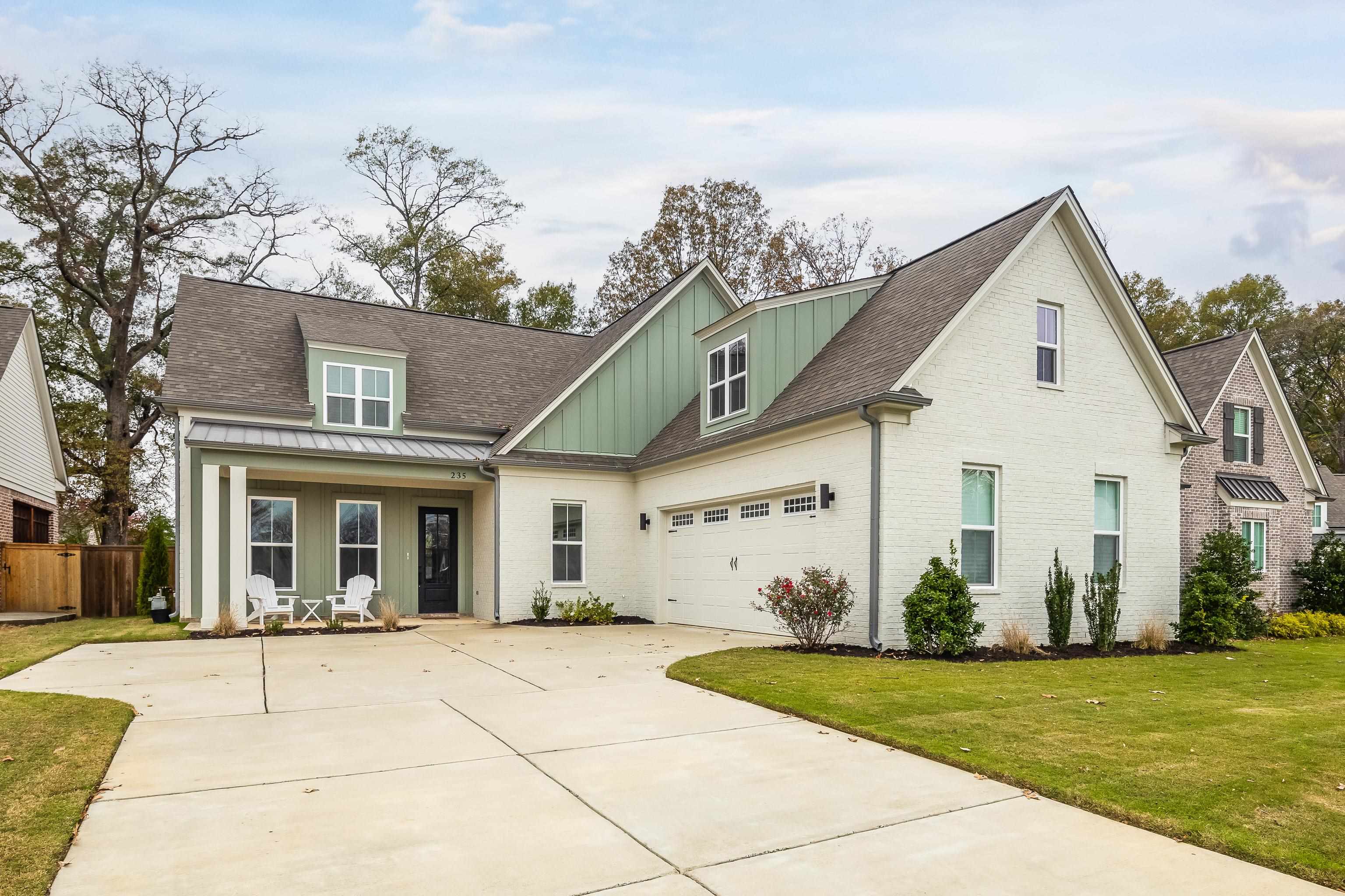 View of front of house with a porch, a garage, and a front lawn