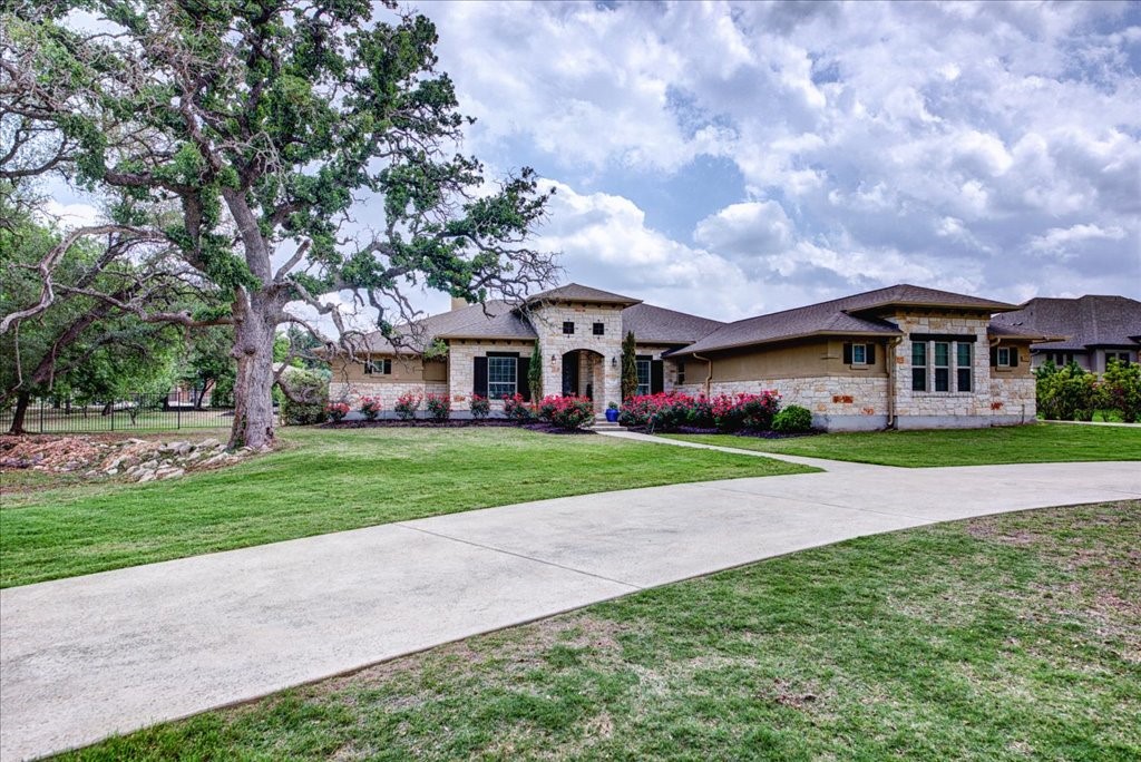 a view of house in front of a big yard with large trees