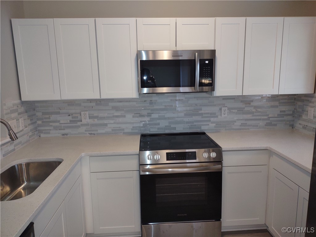 Kitchen featuring white cabinets, decorative backs