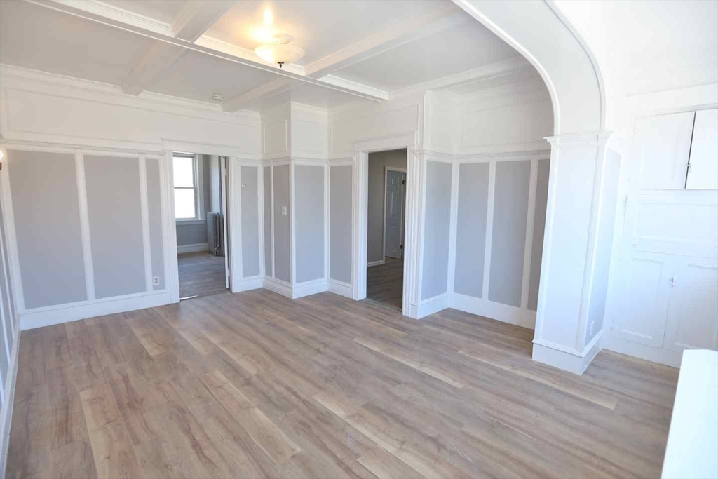 an empty room with wooden floor & windows