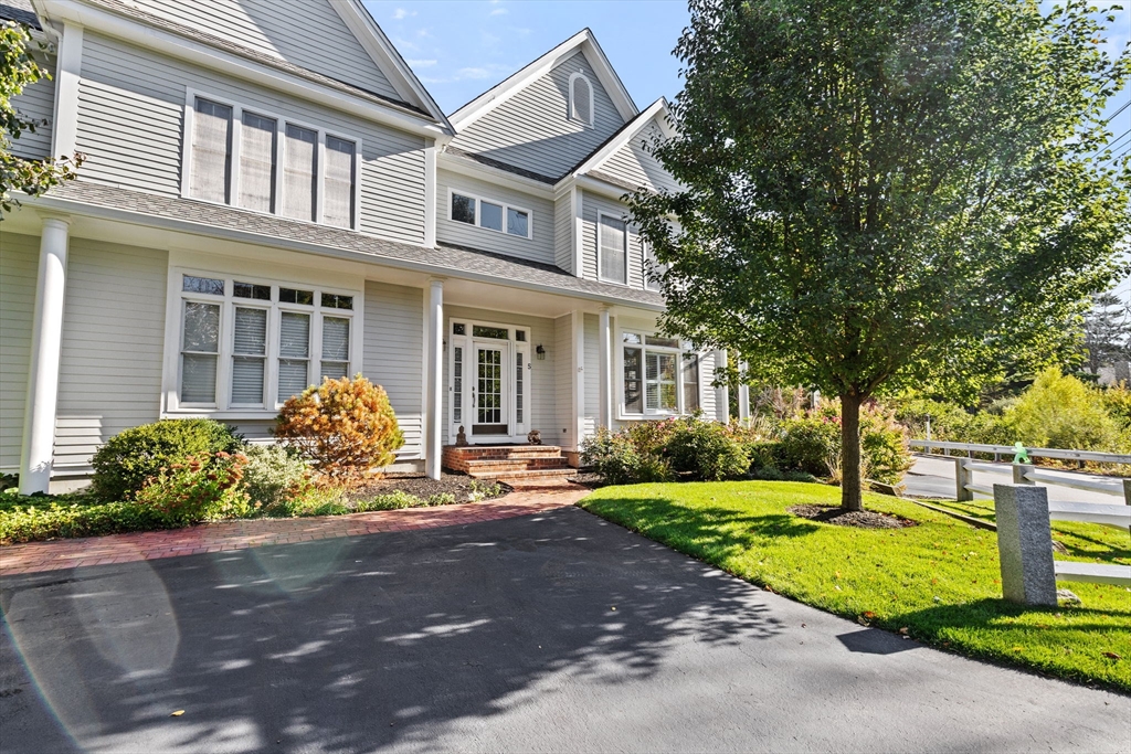 a front view of a house with garden and trees